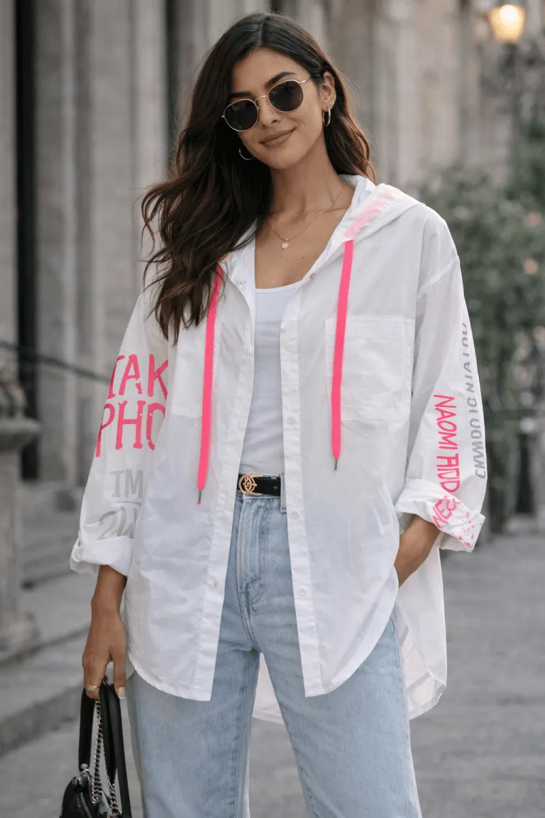 Urban Cotton Blusenjacke: Frau mit Sonnenbrille trägt weiße Kapuzenbluse mit pinken Details. Modische Damenbekleidung.