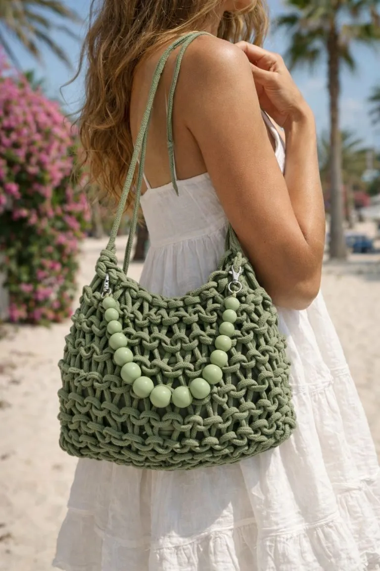 Eine Frau hält eine grüne Santorini-Sommertasche mit klobigen Perlen - geräumig, stilvoll und perfekt für den Strandurlaub oder den täglichen Gebrauch.