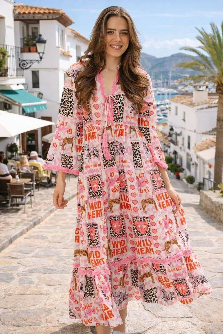 Frau modelliert Wild Heart Tunikakleid mit rosa Tierdruck-leicht, stilvoll, perfekt für Küstentage. Inklusive landschaftlichem Hintergrund.