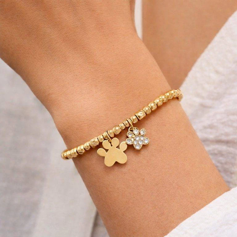 Nahaufnahme: Giuno Lucky Paw Gold Edition Armband mit Pfotenanhängern am Handgelenk. Goldene Perlen & Pfoten-Charms.