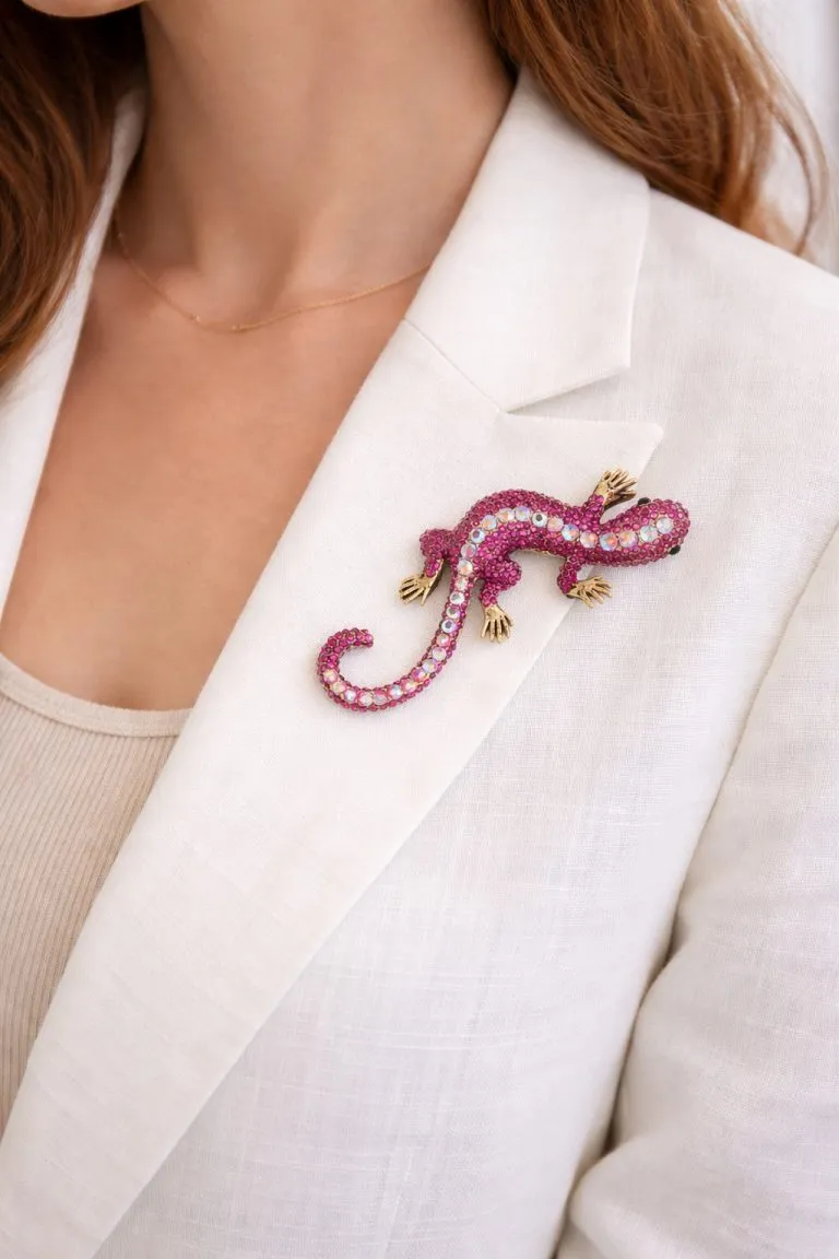 Close-up of the Geko Brosche (Kopie), a pink jeweled gecko brooch with golden accents, pinned to a white linen blazer.