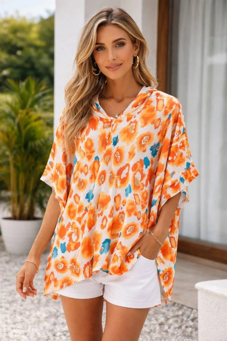 Attraktive Frau im orangefarbenen Sommer-Poncho und weißen Shorts. Stilvolle Mode für warme Tage.