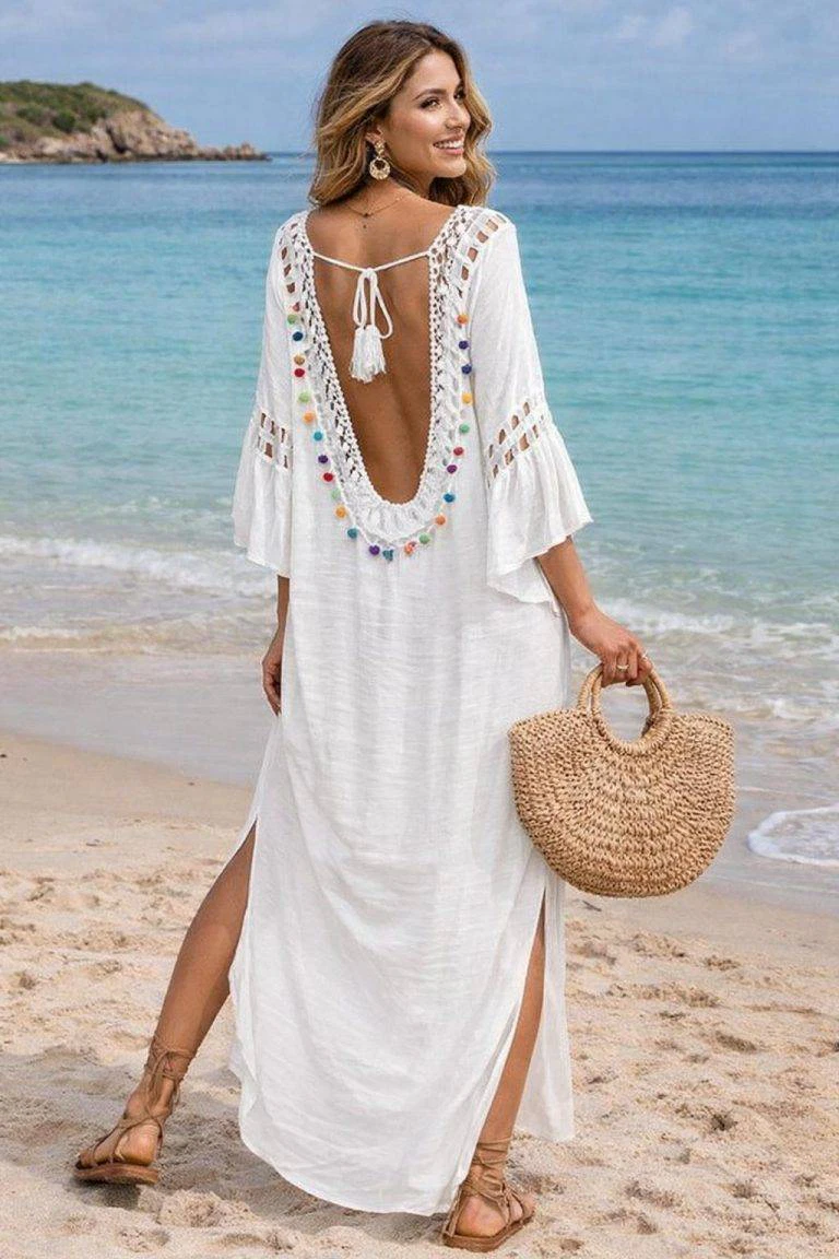 Strandkleid Model in Weiß: Sommerlicher Look mit bunten Pompons und Stroh Tasche am Strand. 
