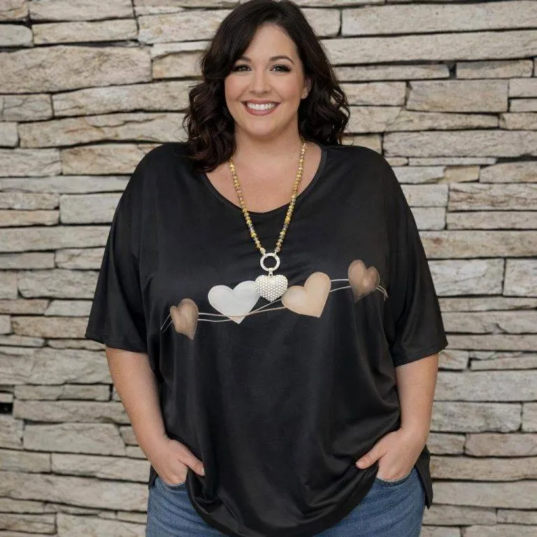 Herzmoment Tunika Shirt, schwarzes Shirt mit Herzmotiv und Model vor Steinwand. Bequeme Tunika in Schwarz.